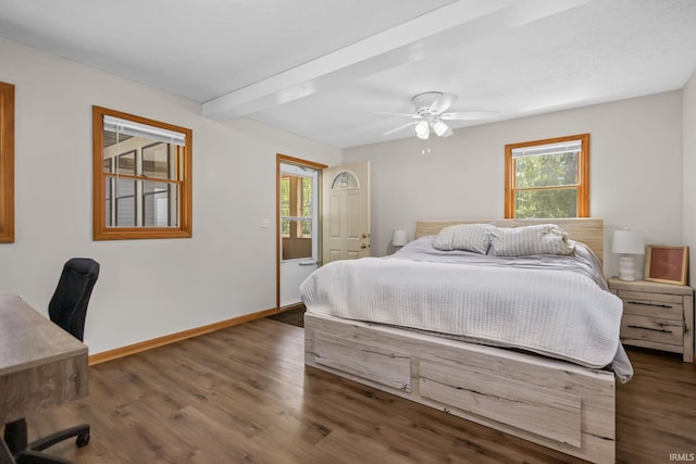 bedroom with wood finished floors, an office area, baseboards, beamed ceiling, and a ceiling fan