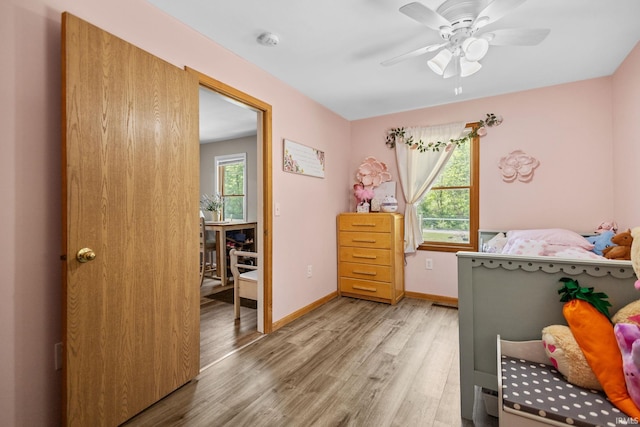 bedroom featuring multiple windows, light wood-type flooring, baseboards, and ceiling fan