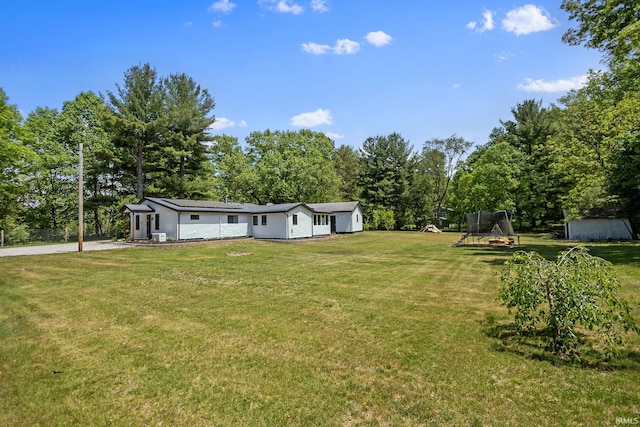 view of grassy yard featuring a playground and view of wooded area