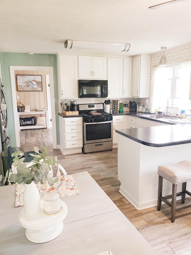 301 Raleigh Rd, Galveston, IN 46932 - kitchen featuring black microwave, gas stove, a sink, white cabinets, and decorative backsplash