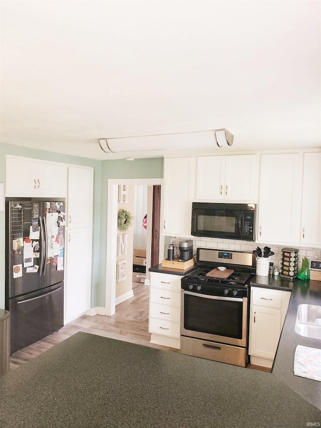 301 Raleigh Rd, Galveston, IN 46932 - kitchen with appliances with stainless steel finishes, white cabinets, decorative backsplash, dark countertops, and a sink
