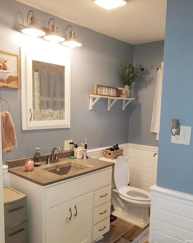 301 Raleigh Rd, Galveston, IN 46932 - bathroom with a wainscoted wall, toilet, wood finished floors, and vanity