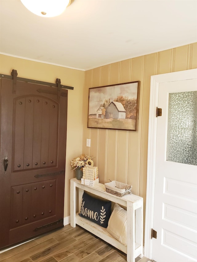 301 Raleigh Rd, Galveston, IN 46932 - entrance foyer with wood finished floors, ornamental molding, a barn door, and baseboards