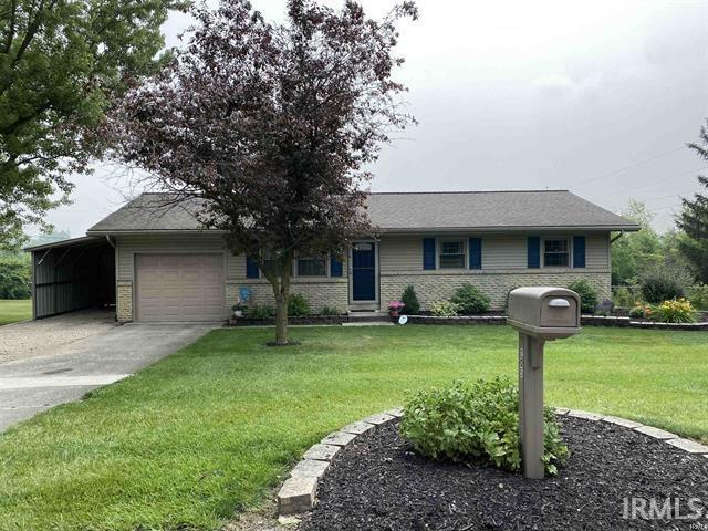 205 Holly Ln, Geneva, IN 46740 - single story home featuring concrete driveway, brick siding, a front lawn, a garage, and an attached carport