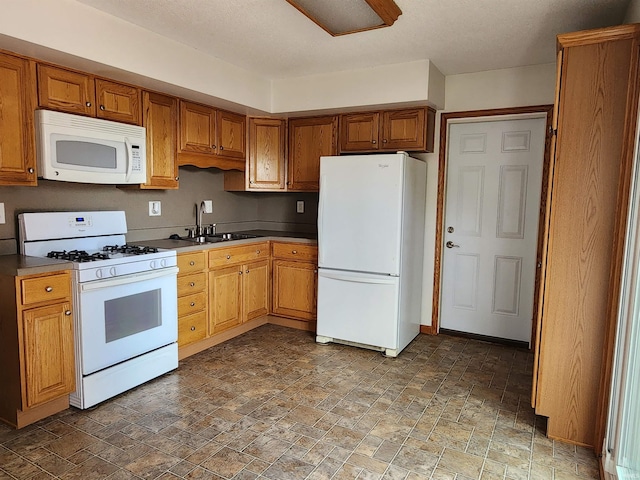 205 Holly Ln, Geneva, IN 46740 - kitchen with white appliances, a sink, stone finish floors, brown cabinetry, and dark countertops