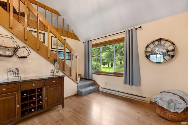 103 Ironwood Ave, Kendallville, IN 46755 - bar featuring a baseboard radiator, light wood finished floors, stairway, and vaulted ceiling