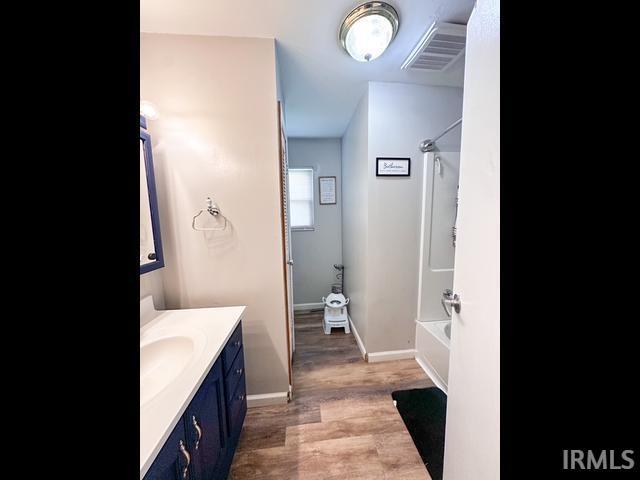 11239 Thomas Dr, Evansville, IN 47712 - bathroom with vanity, shower / bathtub combination, wood finished floors, and baseboards