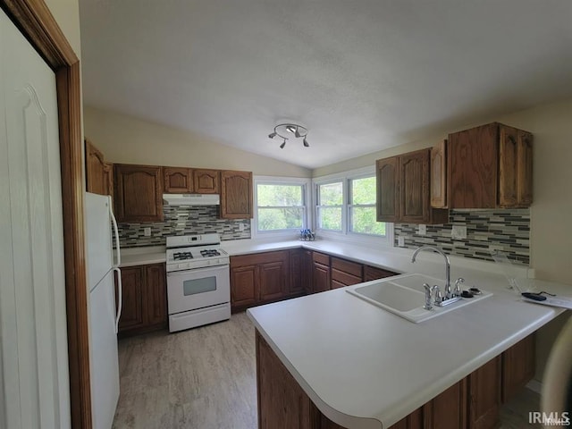 2347 E Navaho Dr, Vincennes, IN 47591 - kitchen with white appliances, under cabinet range hood, a sink, a peninsula, and tasteful backsplash