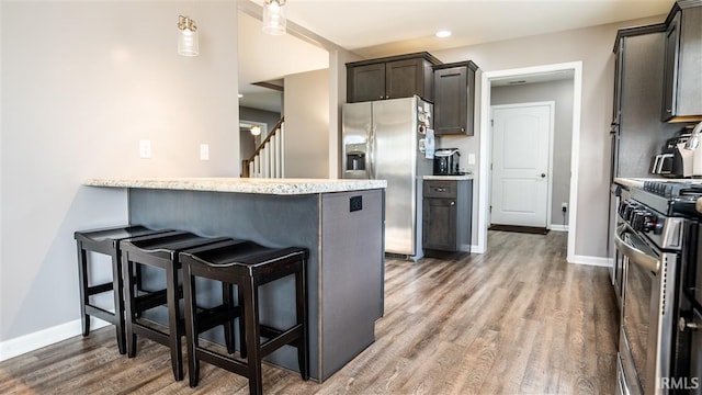 2014 Buell Dr, Angola, IN 46703 - kitchen featuring appliances with stainless steel finishes, a kitchen breakfast bar, light wood finished floors, baseboards, and recessed lighting