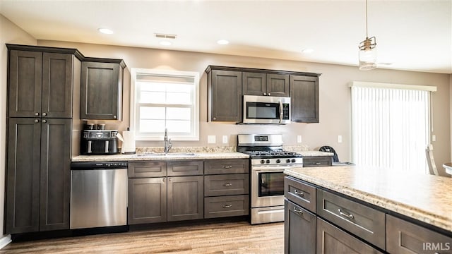 2014 Buell Dr, Angola, IN 46703 - kitchen with stainless steel appliances, a sink, dark brown cabinets, light wood-style flooring, and light stone counters
