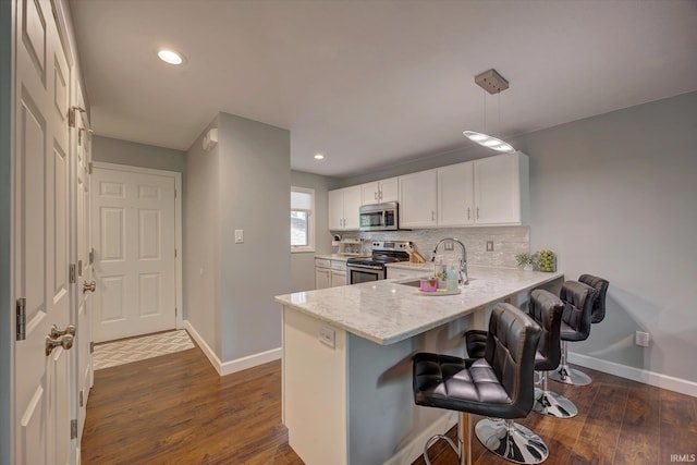 1881 E Eagle Bay Dr, Bloomington, IN 47401 - kitchen with stainless steel appliances, a sink, a breakfast bar, dark wood-style flooring, and baseboards