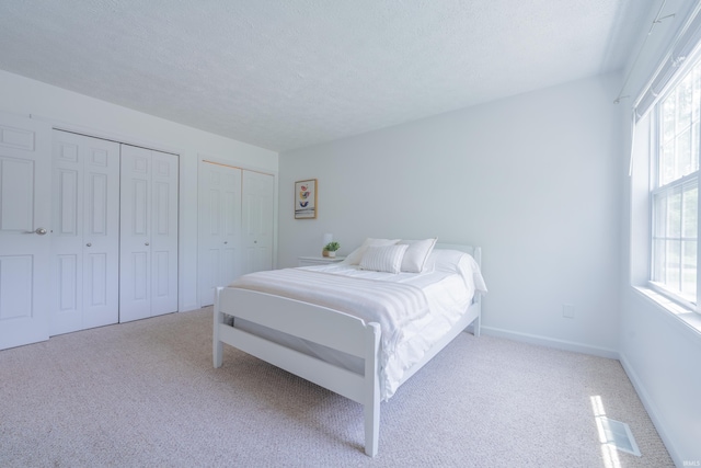 3417 S Westminster Way, Bloomington, IN 47401 - bedroom featuring two closets, carpet, multiple windows, and a textured ceiling