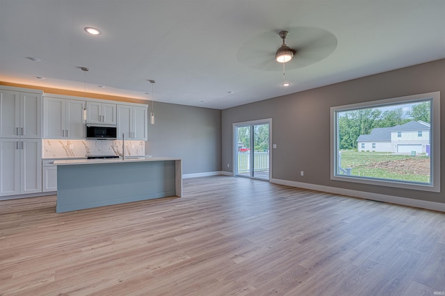 3605 Sand Dr, Newburgh, IN 47630 - kitchen featuring stainless steel microwave, open floor plan, light wood-style flooring, tasteful backsplash, and baseboards