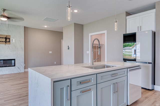 3605 Sand Dr, Newburgh, IN 47630 - kitchen with freestanding refrigerator, a sink, ceiling fan, light stone counters, and light wood finished floors