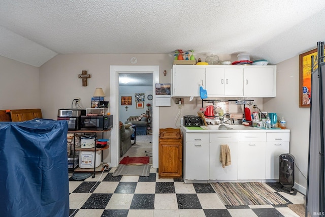 1437 Oakland St, Fort Wayne, IN 46808 - kitchen featuring black microwave, light flooring, light countertops, white cabinets, and lofted ceiling