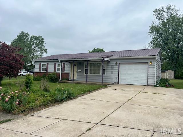 406 E Maple St, Attica, IN 47918 - ranch-style house with an attached garage, concrete driveway, covered porch, and a front yard