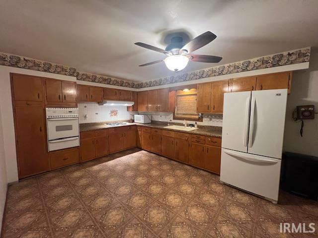 406 E Maple St, Attica, IN 47918 - kitchen with white appliances, a warming drawer, a sink, brown cabinets, and under cabinet range hood