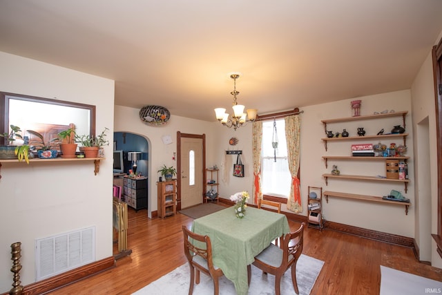 1422 Virginia St, Lafayette, IN 47905 - dining area with a chandelier, light wood-style floors, arched walkways, and baseboards