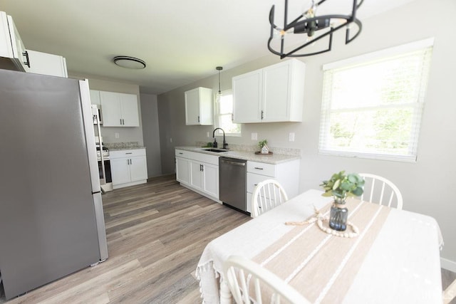 904 Hall Ave, Oolitic, IN 47446 - kitchen featuring appliances with stainless steel finishes, a sink, light wood finished floors, white cabinets, and a chandelier