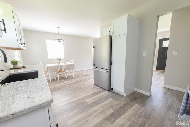 904 Hall Ave, Oolitic, IN 47446 - kitchen featuring freestanding refrigerator, white cabinets, light stone countertops, and light wood-type flooring