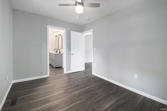 10974 County Road 10, Middlebury, IN 46540 - unfurnished bedroom featuring baseboards, dark wood-style flooring, a sink, a ceiling fan, and connected bathroom