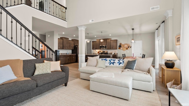 5263 Gadwall Pass, Fort Wayne, IN 46818 - living room featuring light wood-style flooring, ornate columns, recessed lighting, stairs, and a high ceiling