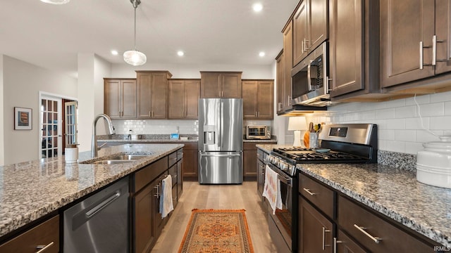 5263 Gadwall Pass, Fort Wayne, IN 46818 - kitchen featuring appliances with stainless steel finishes, a sink, stone counters, light wood-style flooring, and tasteful backsplash