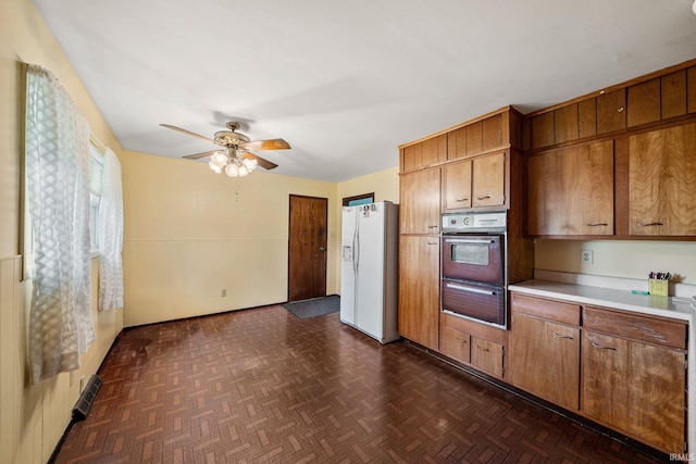 1212 Michigan Ave, Mishawaka, IN 46544 - kitchen with white fridge with ice dispenser, wall oven, brown cabinetry, a ceiling fan, and light countertops