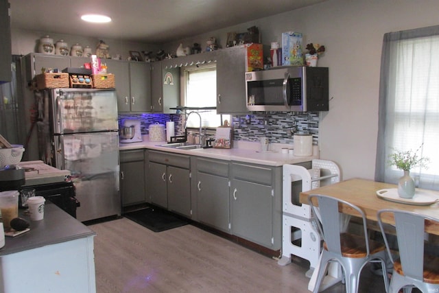 1908 E 18th St, Muncie, IN 47302 - kitchen featuring appliances with stainless steel finishes, backsplash, gray cabinetry, a sink, and light wood finished floors