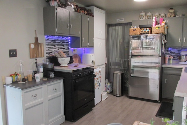 1908 E 18th St, Muncie, IN 47302 - kitchen with freestanding refrigerator, black range with electric cooktop, backsplash, and light wood-type flooring