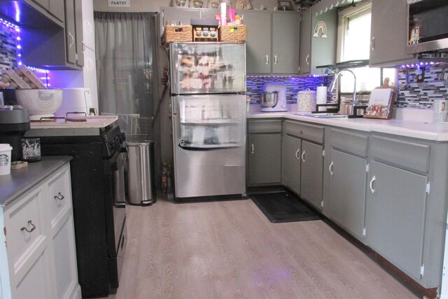1908 E 18th St, Muncie, IN 47302 - kitchen featuring appliances with stainless steel finishes, gray cabinets, backsplash, light wood finished floors, and a sink