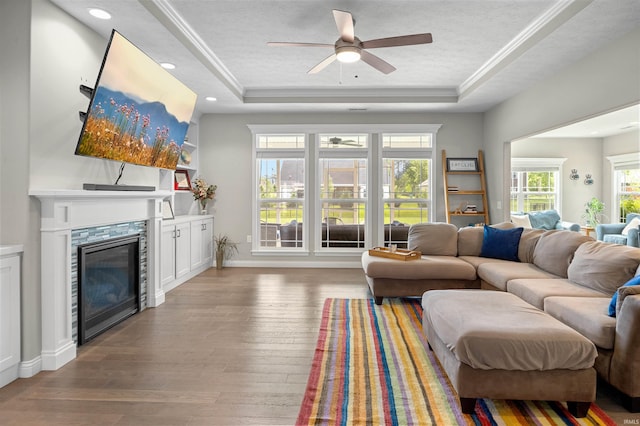 1159 Chesapeake Pointe Dr, Lafayette, IN 47909 - living area featuring a tray ceiling, a ceiling fan, a glass covered fireplace, hardwood / wood-style floors, and ornamental molding