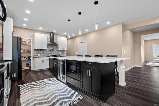 30474 Jaxon Dr, Elkhart, IN 46517 - kitchen featuring wine cooler, built in microwave, dark cabinets, wall chimney range hood, and white cabinetry