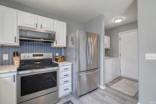 3063 N Natasha Dr, Bloomington, IN 47404 - kitchen with appliances with stainless steel finishes, washing machine and clothes dryer, light countertops, and light wood finished floors