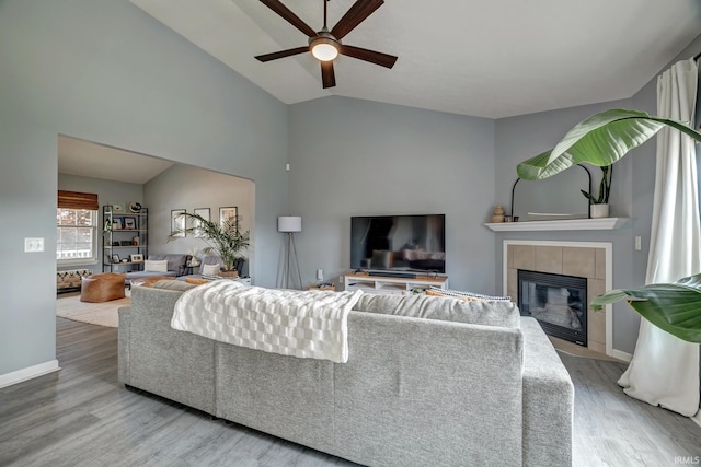 3063 N Natasha Dr, Bloomington, IN 47404 - living area featuring wood finished floors, a ceiling fan, a fireplace, vaulted ceiling, and baseboards
