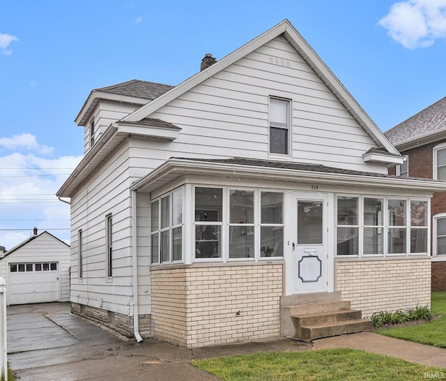 715 W 7th St, Mishawaka, IN 46544 - view of front of house with entry steps, brick siding, driveway, an outbuilding, and a chimney