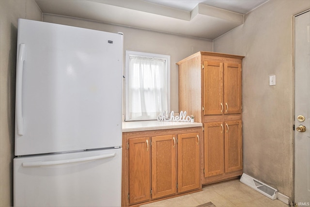 715 W 7th St, Mishawaka, IN 46544 - kitchen featuring freestanding refrigerator, light countertops, brown cabinetry, and light tile patterned floors
