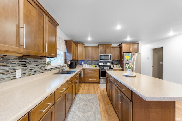 914 W 300 S, Bluffton, IN 46714 - kitchen featuring appliances with stainless steel finishes, a sink, light wood-style floors, brown cabinetry, and a center island