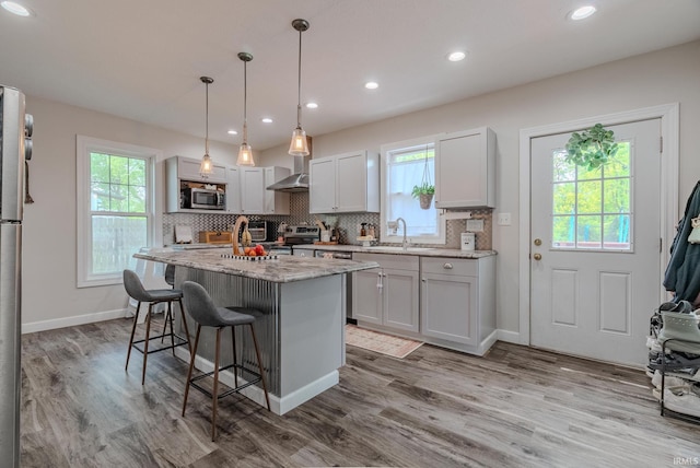 21 Noble St, Wabash, IN 46992 - kitchen featuring wall chimney exhaust hood, a kitchen bar, plenty of natural light, appliances with stainless steel finishes, and recessed lighting