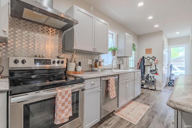 21 Noble St, Wabash, IN 46992 - kitchen with stainless steel appliances, extractor fan, a sink, light wood finished floors, and backsplash