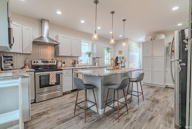 21 Noble St, Wabash, IN 46992 - kitchen with stainless steel appliances, wall chimney range hood, a sink, light wood-type flooring, and backsplash