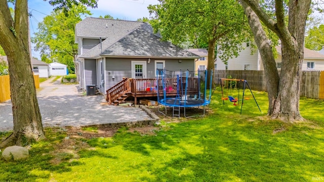 21 Noble St, Wabash, IN 46992 - back of property featuring a shingled roof, a wooden deck, a patio area, cooling unit, and a trampoline