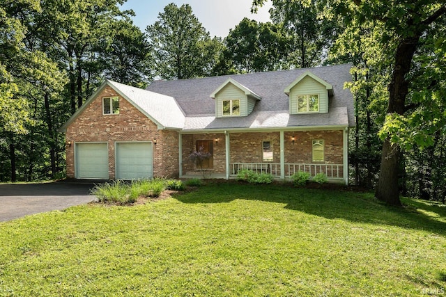 2557 S Smith Rd, Bloomington, IN 47401 - cape cod home featuring covered porch, asphalt driveway, brick siding, a front yard, and an attached garage
