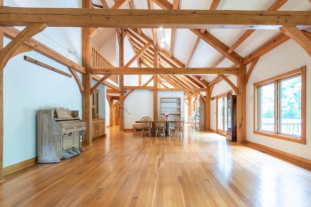 2557 S Smith Rd, Bloomington, IN 47401 - unfurnished living room featuring light wood-type flooring, baseboards, high vaulted ceiling, and beam ceiling