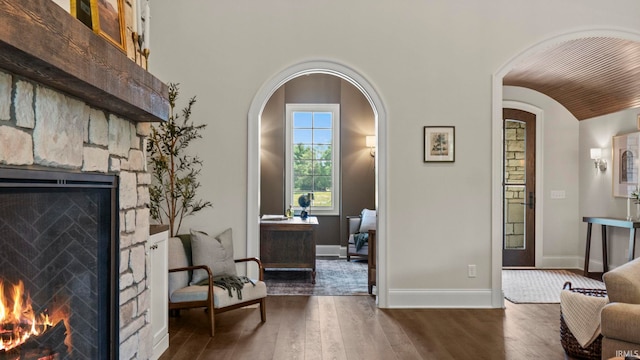 447 E Basalt Dr, Huntertown, IN 46748 - living area with a stone fireplace, arched walkways, dark wood-style flooring, and baseboards