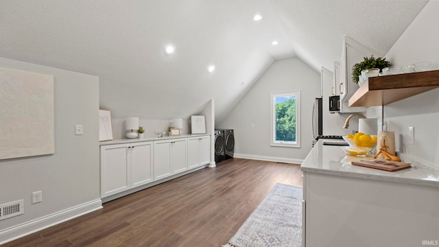 447 E Basalt Dr, Huntertown, IN 46748 - kitchen with washing machine and dryer, open shelves, white cabinetry, dark wood-style floors, and vaulted ceiling