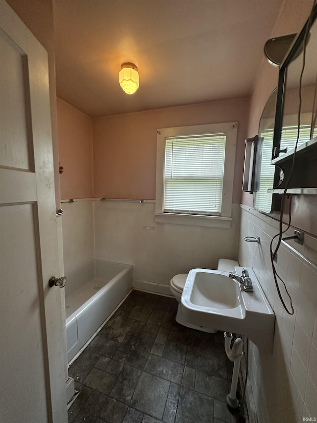 539 NE 9th St, Linton, IN 47441 - bathroom featuring stone tile flooring, toilet, a bathtub, and a sink
