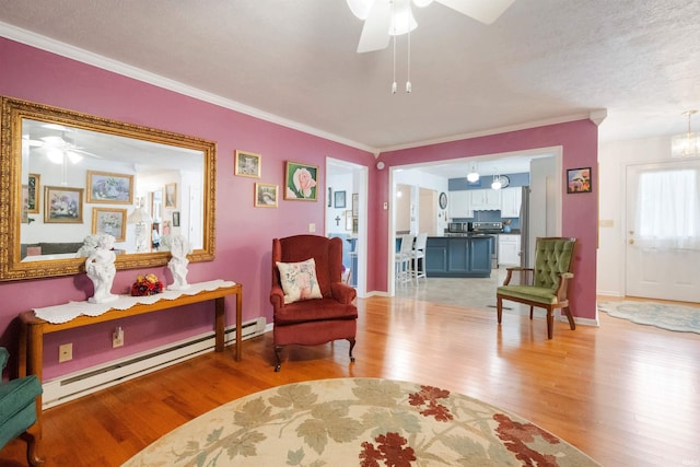404 S Maple St, Greentown, IN 46936 - living room featuring a ceiling fan, a baseboard heating unit, light wood-type flooring, ornamental molding, and baseboards