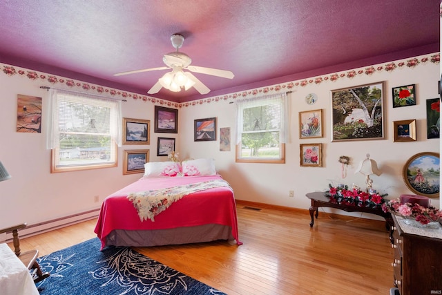 404 S Maple St, Greentown, IN 46936 - bedroom with a baseboard radiator, multiple windows, light wood-style floors, a textured ceiling, and baseboards
