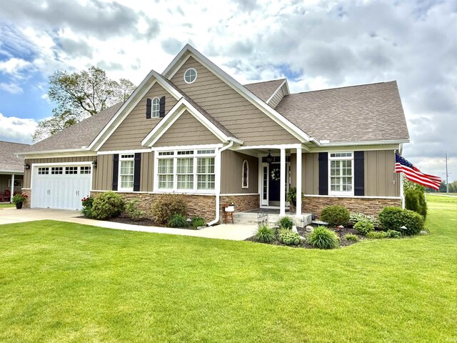 4968 W Campbell St, North Judson, IN 46366 - craftsman house with board and batten siding, a garage, stone siding, a front lawn, and a shingled roof